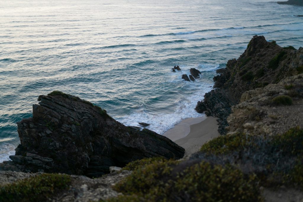 a couple of rocks sitting on top of a beach next to the ocean