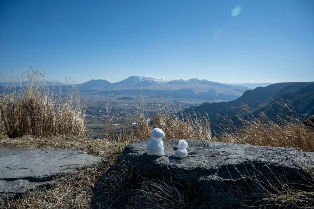 a couple of snowmen sitting on top of a rock